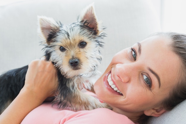 Mujer feliz abrazando a su yorkshire terrier en el sofá