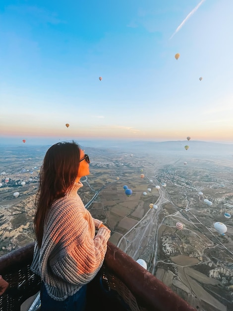 Mujer feliz durante el amanecer viendo globos aerostáticos en capadocia turquía