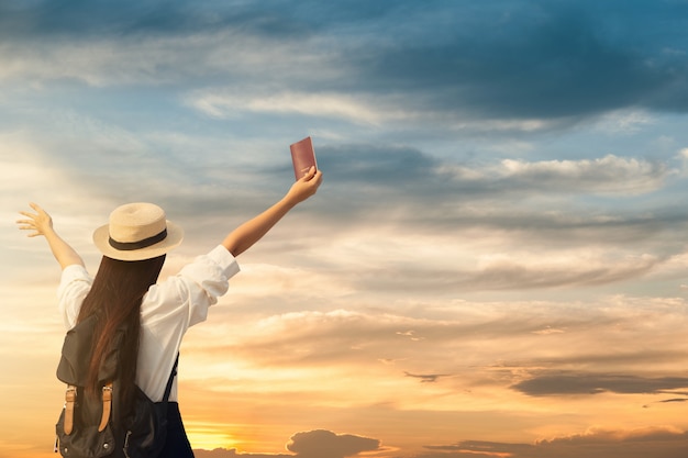 Mujer feliz aparece pasaporte con puesta de sol.