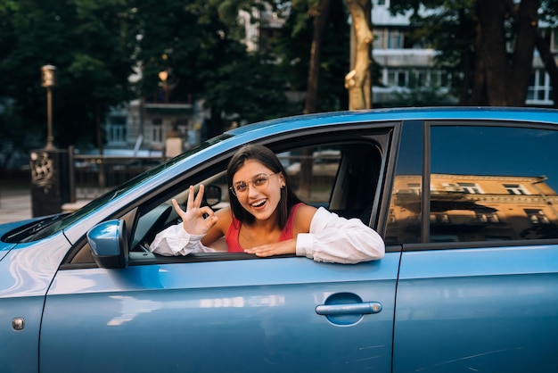 Mujer feliz en un auto mirando por la ventana