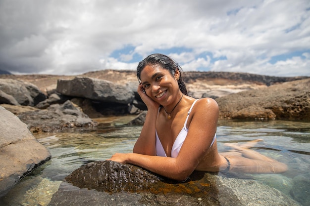 Una mujer feliz se baña junto al mar en un estanque cristalino relajación de verano