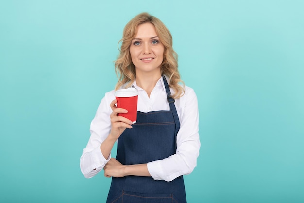 Mujer feliz barista en delantal de cocinero beber café para llevar, por la mañana.