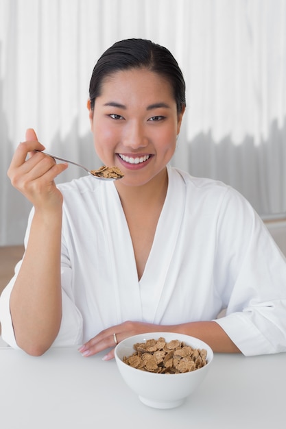 Mujer feliz en bata de baño desayunando