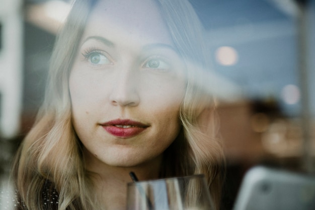 Foto mujer feliz con una bebida y un teléfono mirando por la ventana