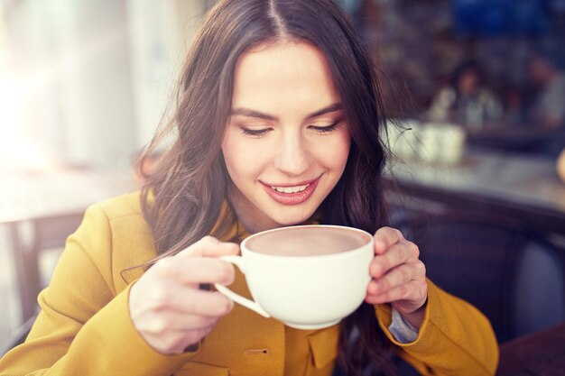 mujer feliz bebiendo cacao en el café de la calle de la ciudad