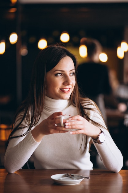 Mujer feliz bebiendo café en un café