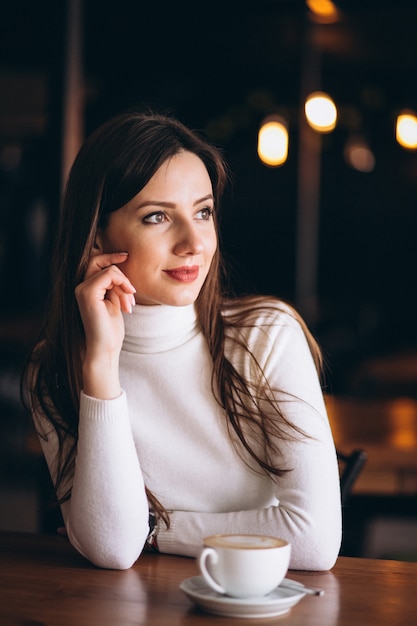 Mujer feliz bebiendo café en un café