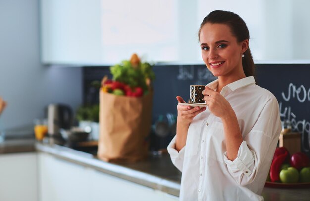 Mujer feliz bebiendo té en la cocina de casa