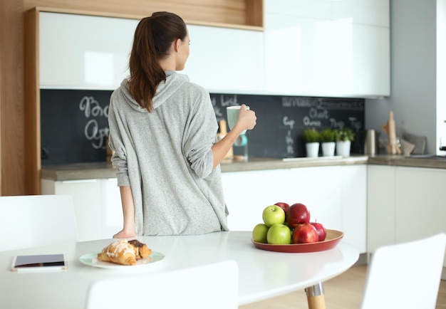 Mujer feliz bebiendo té en la cocina de casa