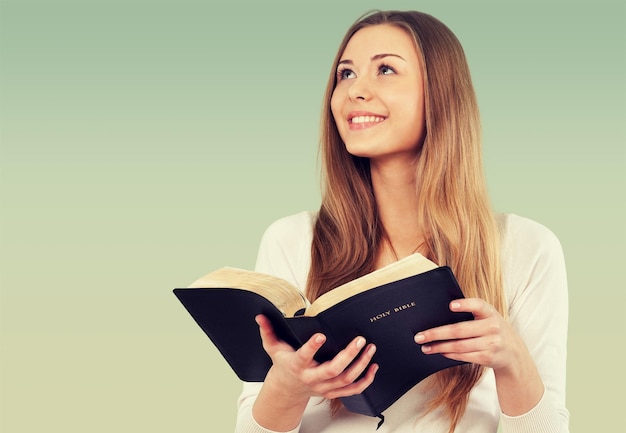 Mujer feliz con Biblia sobre fondo claro