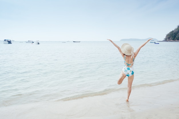 Mujer feliz del bikini en el cielo de la playa y de las nubes.