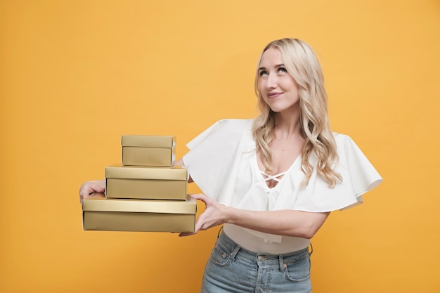 Mujer feliz en blusa blanca sosteniendo un paquete de cajas de regalo