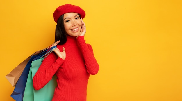 Mujer feliz con bolsas de compras en la mano. fundamento amarillo