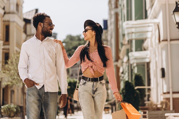 Mujer feliz con bolsas de compras tocando el hombro de su hombre y sonriendo