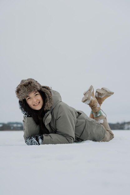 Mujer feliz en el bosque de invierno disfrutando de la primera nieve Una joven con un sombrero se está divirtiendo en la naturaleza de invierno Estilo de vida