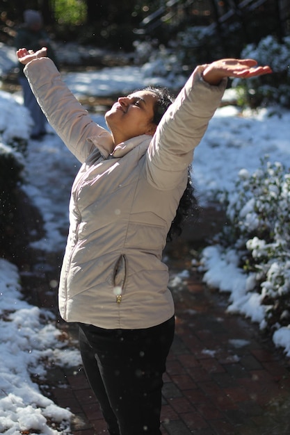 Foto mujer feliz con los brazos levantados usando ropa cálida durante el invierno.