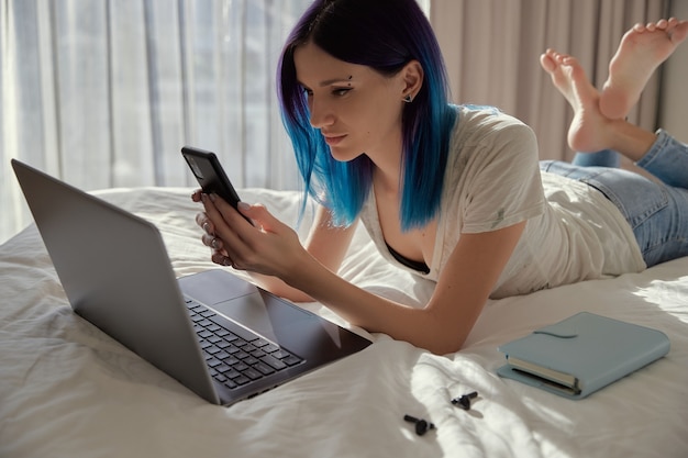 Mujer feliz con cabello azul en el trabajo de dormitorio con portátil