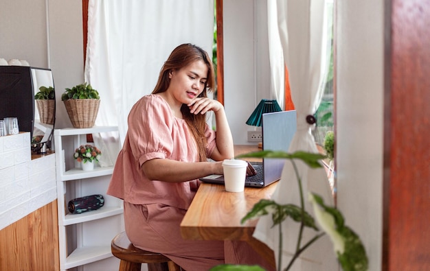 Una mujer feliz en un café usando una computadora portátil joven mujer blanca sentada ocupada trabajando en su computadora portátil