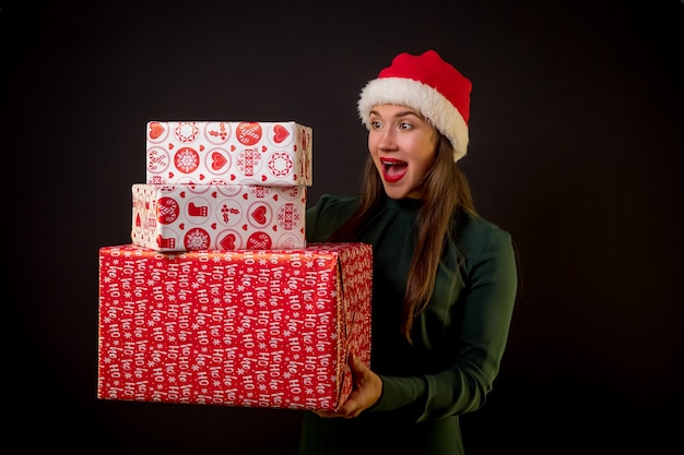 Mujer feliz con cajas de regalo de Navidad sobre fondo negro