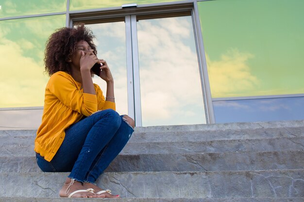 La mujer feliz en la calle hablando por teléfono