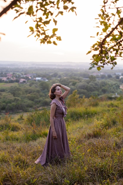 Mujer feliz camina al atardecer en una colina con vistas al río