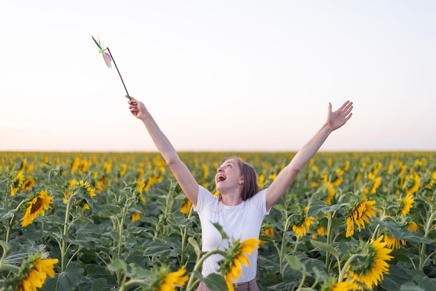 Mujer feliz camina por el campo de girasoles. Manos levantadas.