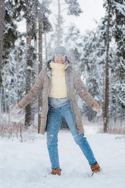 Foto mujer feliz caminando al aire libre en un día de invierno cubierto de nieve modelo femenino vestido con nieve gris divirtiéndose