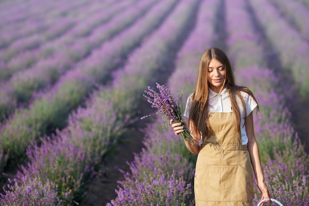 Mujer feliz caminando con flores en campo lavanda