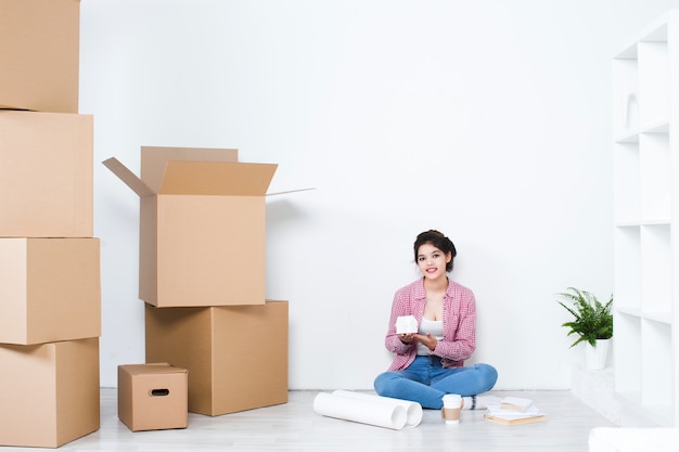 Mujer feliz en una casa nueva cerca de cajas