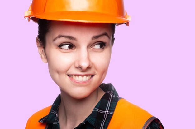 mujer feliz en casco de seguridad chaleco naranja fondo rosa