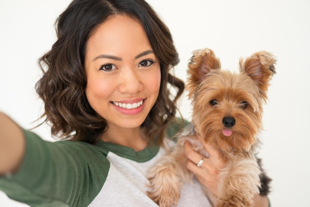 Mujer feliz celebración de Yorkie y tomando Selfie