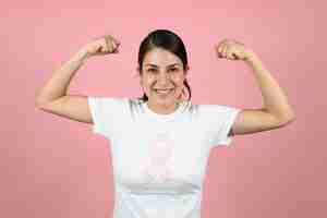 Foto mujer feliz con cinta en fondo rosado concepto de concienciación sobre el cáncer de mama