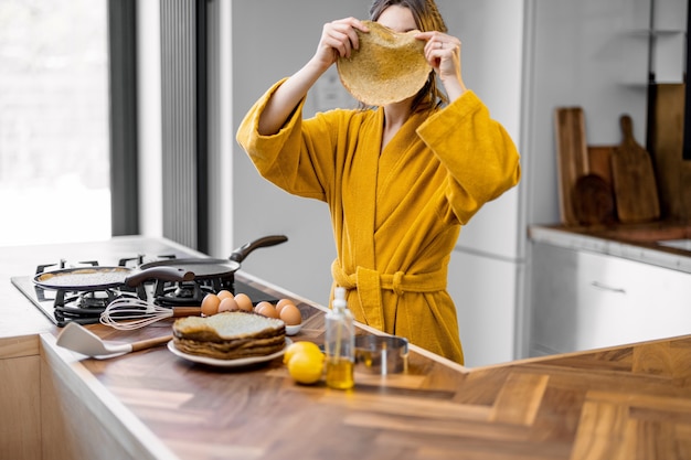 Mujer feliz cocinando panqueques para el desayuno