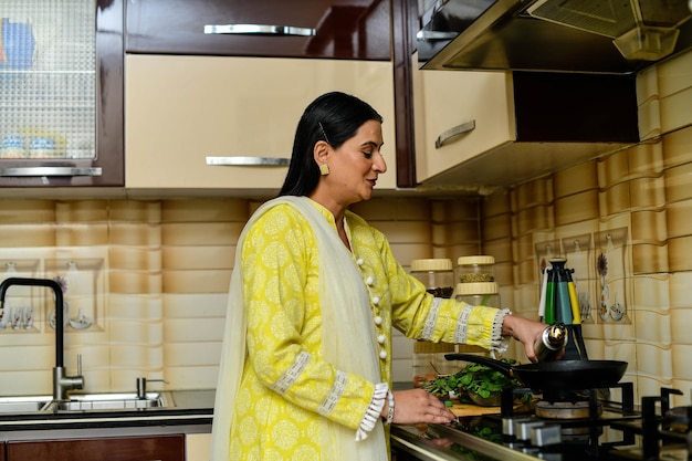 Mujer feliz cocinando en su cocina modelo paquistaní indio