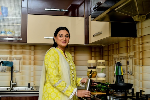 Mujer feliz cocinando en su cocina modelo paquistaní indio