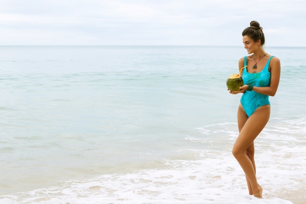 Mujer feliz con un coco en la playa