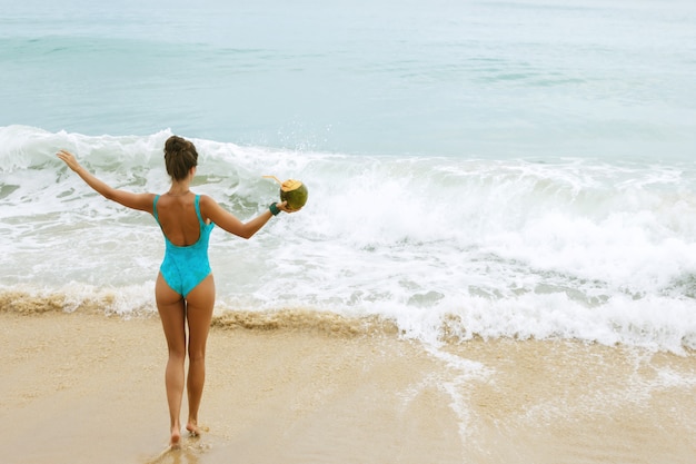 Mujer feliz con un coco en la playa