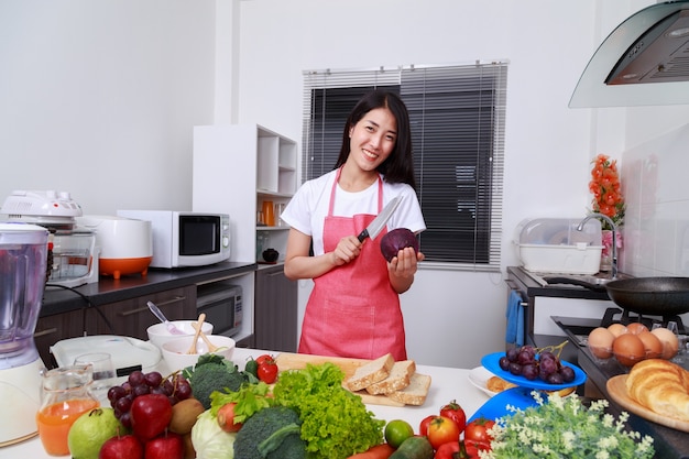 mujer feliz con col morada y cuchillo en la cocina