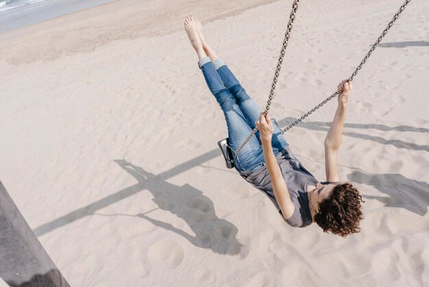 Mujer feliz en un columpio en la playa