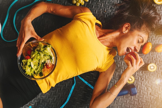 Mujer feliz come sano y entrena en el gimnasio