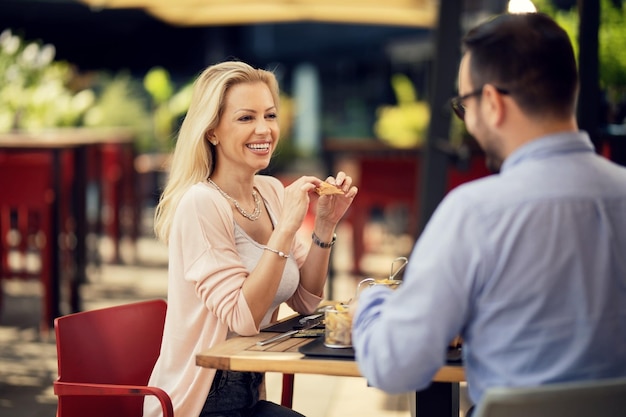 Mujer feliz comunicándose con su novio mientras comen juntos en un restaurante