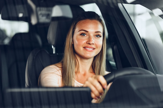 Mujer feliz conduciendo un coche y sonriendo