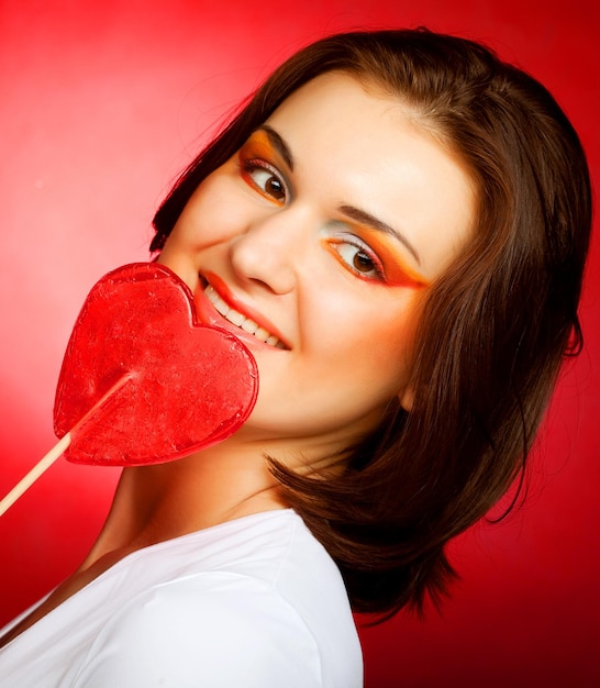 Foto mujer feliz con corazón candy lolly pop