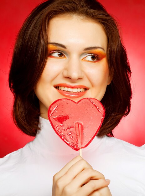 Mujer feliz con corazón caramelo lolly pop.