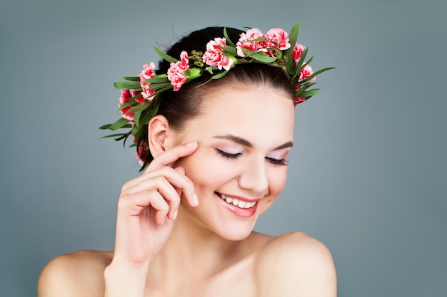 Mujer feliz con corona de flores sobre fondo azul.