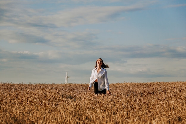 Mujer feliz corre en un campo de trigo en un día de verano. Concepto de felicidad y alegría