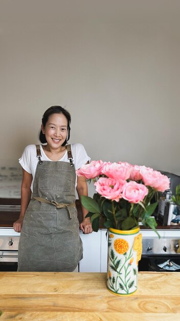 Foto mujer feliz con delantal en una habitación con flores