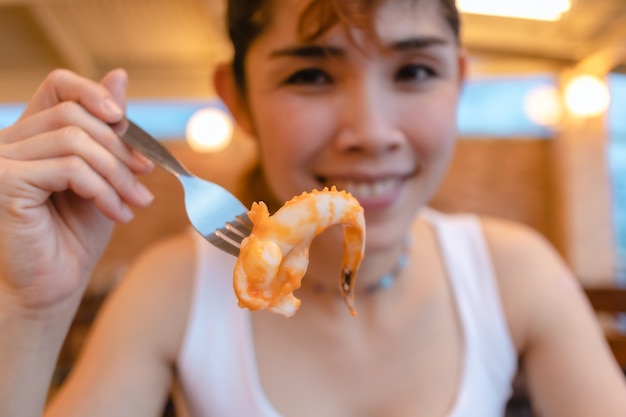 Mujer feliz disfruta comiendo calamares mariscos en las vacaciones de verano