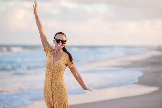 Mujer feliz disfrutando de la hermosa puesta de sol en la playa