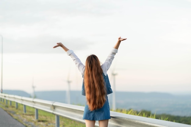 Mujer feliz disfrutando de la vida en el campo con bosque Naturaleza belleza azul cielo nublado y colorido campo con naturaleza Estilo de vida al aire libre Concepto de libertad